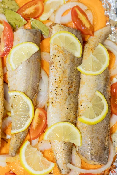 Fırında limonlu, domatesli, havuçlu ve soğanlı fırında pişmiş çiğ hake. Öğlen ya da akşam yemeği için lezzetli balık, diyet için mükemmel. Sebzeli pişirmek için lezzetli ve taze balık..