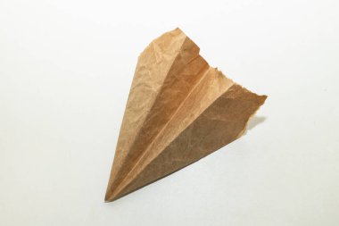 Beyaz arka planda eski, yırtık kahverengi kağıttan yapılmış ev yapımı uçak.