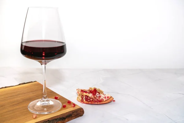 Un bicchiere di vino rosso su una tavola con melograno — Foto Stock