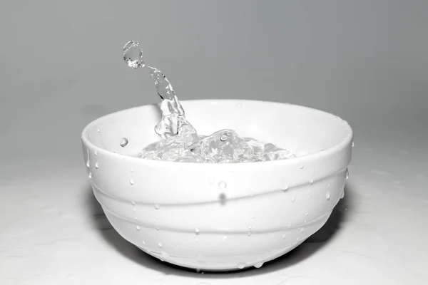 Νερό πιτσιλίζει σε ένα ποτήρι με πάγο σε λευκό φόντο — Φωτογραφία Αρχείου