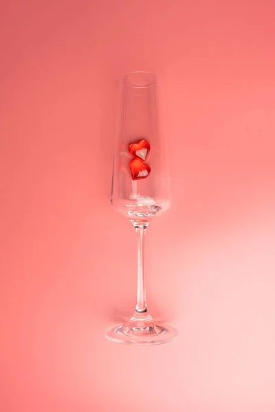 Bicchiere di vino con due cuori su uno sfondo rosa — Foto Stock