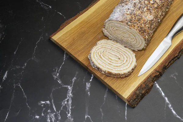 Siyah mermer üzerinde tahta bir tahtanın üzerinde hamur işi rulosu.