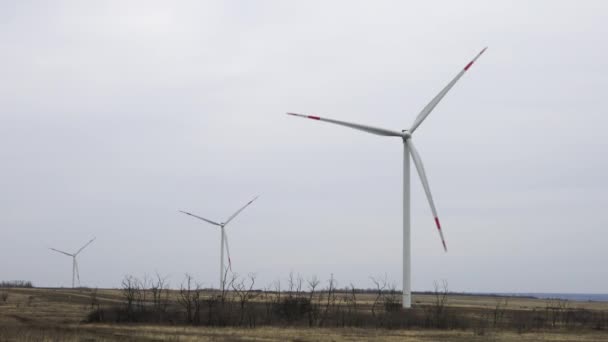 Ветряные турбины в поле против неба — стоковое видео