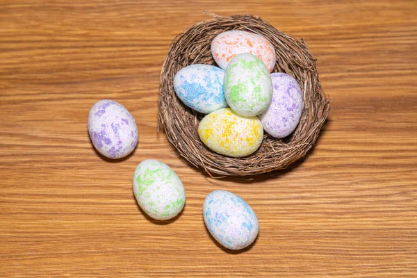 Пасхальные красочные яйца в гнезде крупным планом на деревянном фоне — стоковое фото