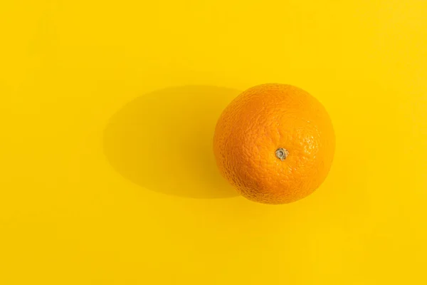 Naranja con una sombra dura sobre un fondo colorido — Foto de Stock