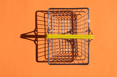 Renkli arka planda sert gölgeli çelik süpermarket sepeti