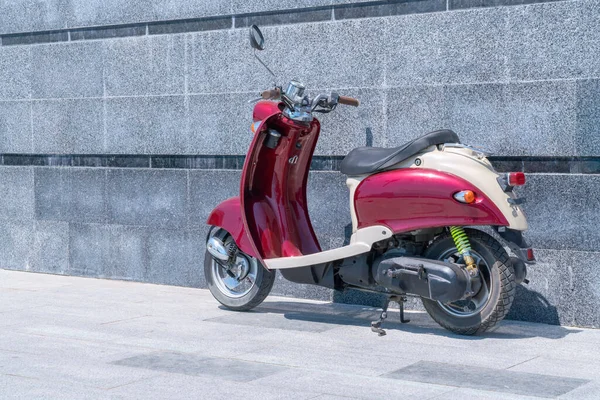 A red scooter standing against a stone wall — Stock Photo, Image