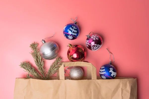 Brinquedos de Natal em um saco de papel em um fundo rosa vista superior — Fotografia de Stock