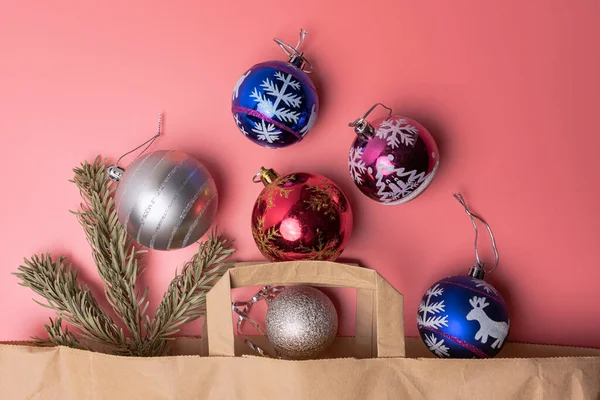 Brinquedos de Natal em um saco de papel em um fundo rosa vista superior — Fotografia de Stock