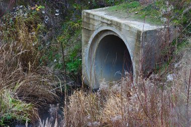 Nehir büyük bir beton boruya akıyor.