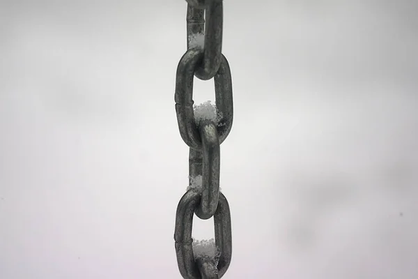 links of a metal chain on a background of white snow