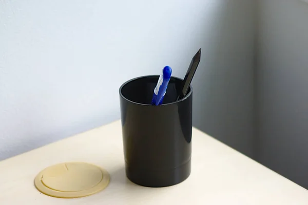 writing instruments in a plastic cup on the table