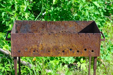 Yeşil çimlerin üzerinde paslı bir metal brazier.