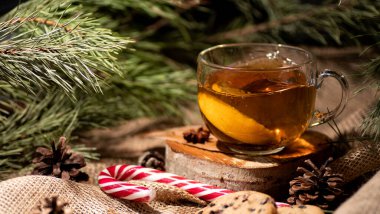 Limonlu çay, arka planda çuval bezi, Noel ağacı ve koni dallarında kurabiyeler ve lolipopun yanında. Bir yazıt için yer.