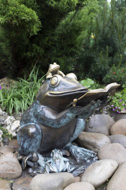 Kurbağalar anıtı olan bir park. Elinde kitap olan bir kurbağanın bronz heykeli. Kurbağa çocuklara okur.