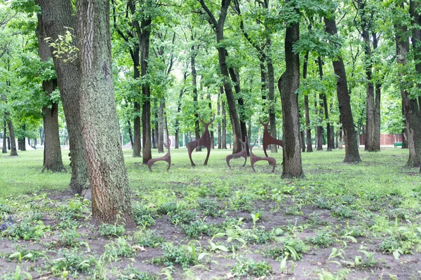 Ağaçlı park, geyik aileli heykeller.