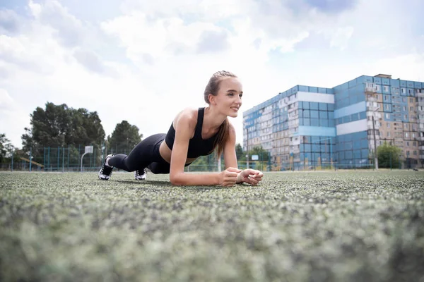 Girl athlete doing exercises in the open air. Bottom view. Sports activities. Sports rack, press, fitness concept.