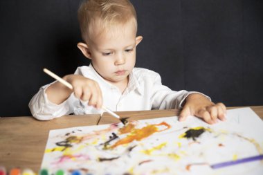 Ressam. Küçük çocuk boyalarla resim çiziyor. Resim yapmak. Sanat