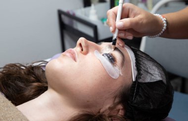 Bir kozmetikçi laminasyon işlemi sırasında kaşlar ve kirpiklerle çalışır.