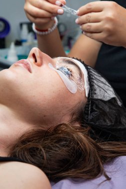 Salondaki bir kadın, uzun ve kalın kirpikleri yapmak için bir prosedür uygulanıyor.