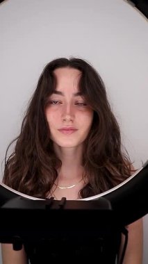 Bir manken güzellik salonundaki kozmetik işlemlerden sonra kamera ve lamba önünde poz verir. Yüze yakın çekim