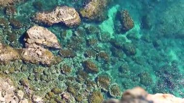 Akdeniz 'in berrak turkuaz suyu ve su altı kayaları, yukarıdan görünüyor.