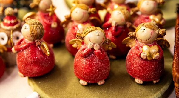 Small clay figurines of Christmas angels in red sparkly dresses. Home decor.