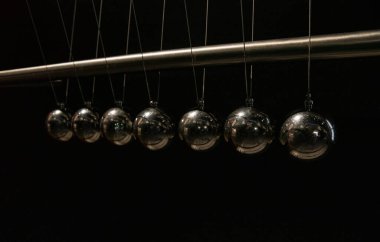 Çelik Newton 'un siyah arka plandaki beşiği momentum ve enerjinin korunumu kanununu gösterir.