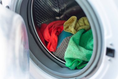 Renkli kirli çamaşırlarla dolu çamaşır makinesi kapısını aç.