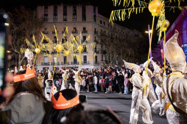 Akşam Barselona sokaklarında üç kralın geçit töreni. Barcelona İspanya Geçit Töreni 'nde Parlak Karnaval kostümlü oyuncular 05.01.2026