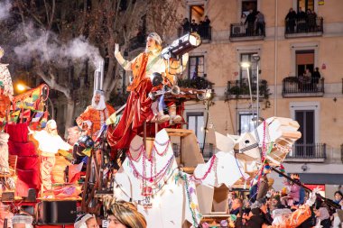 Akşam Barselona sokaklarında üç kralın geçit töreni. Barcelona İspanya Geçit Töreni 'nde Parlak Karnaval kostümlü oyuncular 05.01.2026