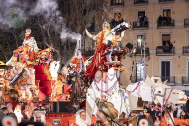 Akşam Barselona sokaklarında üç kralın geçit töreni. Barcelona İspanya Geçit Töreni 'nde Parlak Karnaval kostümlü oyuncular 05.01.2026
