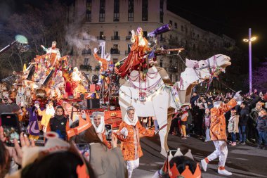 Akşam Barselona sokaklarında üç kralın geçit töreni. Barcelona İspanya Geçit Töreni 'nde Parlak Karnaval kostümlü oyuncular 05.01.2026