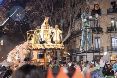 Akşam Barselona sokaklarında üç kralın geçit töreni. Barcelona İspanya Geçit Töreni 'nde Parlak Karnaval kostümlü oyuncular 05.01.2026