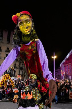 Akşam Barselona sokaklarında üç kralın geçit töreni. Barcelona İspanya Geçit Töreni 'nde Parlak Karnaval kostümlü oyuncular 05.01.2026