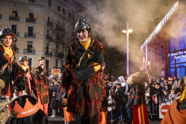 Akşam Barselona sokaklarında üç kralın geçit töreni. Barcelona İspanya Geçit Töreni 'nde Parlak Karnaval kostümlü oyuncular 05.01.2026