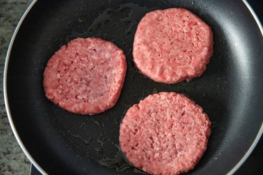Pişirme sırasında tavada çiğ biftek köftesi.
