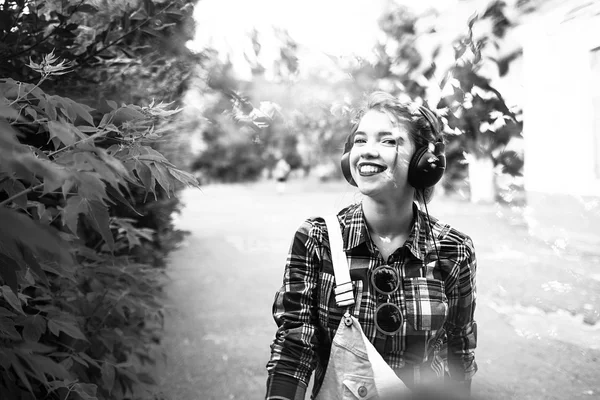 Hipster girl enjoying music on headphones and smiling.
