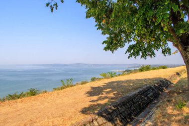 Balatonakarattya, Macaristan. Güneşli bir yaz gününde Balatonakarattya 'nın panoramik manzarası. Turkuaz Balaton Gölü, mavi gökyüzü ve bulutlar..