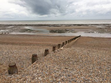 Winchelsea plajı manzarası alçak gelgitte, kumdan çıkan ahşap deniz Groyneleri ile düz kumu ortaya çıkarıyor. 