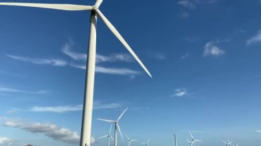Elektrik enerjisi üreten rüzgar türbinleri. Yel değirmeni rüzgar teknolojisi üretimi Rüzgar türbinleri yeşil alanda çiçek açan bir alanda duruyor. 