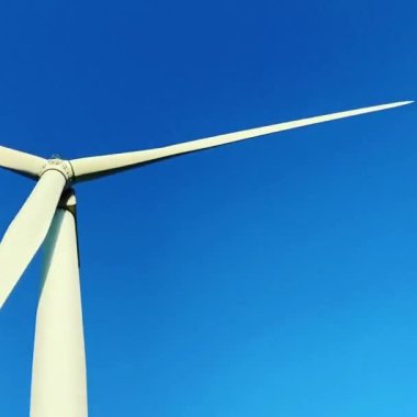 Rüzgar türbinleri elektrik enerjisi üreten pervane çiftlikleri. Rüzgâr değirmeni güç üretimi. Rüzgâr çiftliği türbinleri. Mavi gökyüzü, yenilenebilir sürdürülebilir enerji üretimi ile yeşil alanda açan pervaneler.