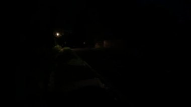 cars driving slowly on a country lane at night