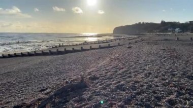 Sunset 'teki Pett Level Plajı. Önünde deniz suyu ve kayalarla dolu bir havuz. Winchelsea Sahili, İngiltere 'nin güney kıyısında, taşlaşmış bir orman olan Pett seviyesindeki kayalıklarla karşılaşıyor.