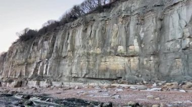 Sunset 'teki Pett Level Plajı. Önünde deniz suyu ve kayalarla dolu bir havuz. Winchelsea Sahili, İngiltere 'nin güney kıyısında, taşlaşmış bir orman olan Pett seviyesindeki kayalıklarla karşılaşıyor.