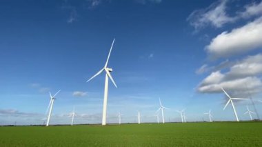 Elektrik enerjisi üreten rüzgar türbinleri. Rüzgâr değirmeni güç üretimi. Mavi gökyüzü ile yeşil alanda duran rüzgar türbinleri. Stok görüntüleri.