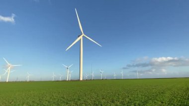 Elektrik enerjisi üreten rüzgar türbinleri. Rüzgâr değirmeni güç üretimi. Mavi gökyüzü ile yeşil alanda duran rüzgar türbinleri. Stok görüntüleri.