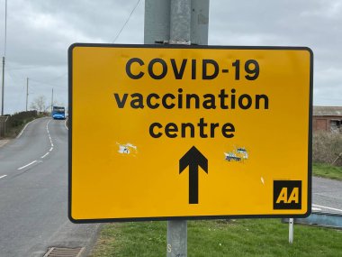 Covid-19 Aşılama Merkezi, New Romney, Doğu Sussex, İngiltere - 03.03.2021: Covid-19 Aşılama Merkezi 'ne giden sarı yol tabelası.