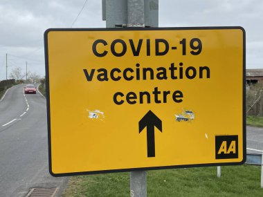 Covid-19 Aşılama Merkezi, New Romney, Doğu Sussex, İngiltere - 03.03.2021: Covid-19 Aşılama Merkezi 'ne giden sarı yol tabelası.