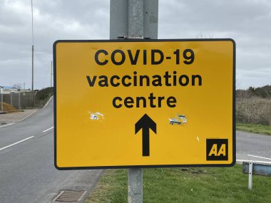 Covid-19 Aşılama Merkezi, New Romney, Doğu Sussex, İngiltere - 03.03.2021: Covid-19 Aşılama Merkezi 'ne giden sarı yol tabelası.